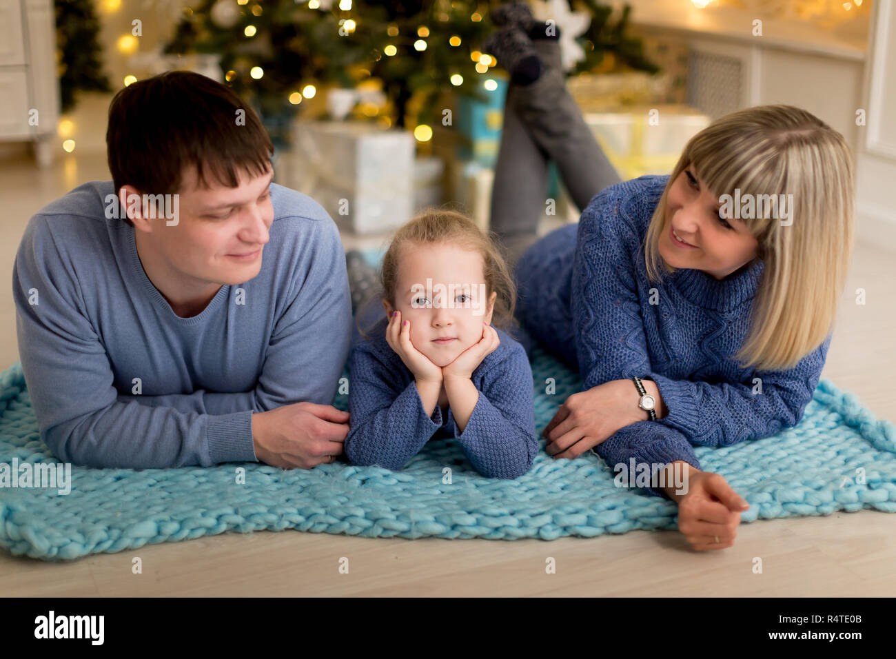 Famiglia giovane su un plaid blu nei pressi di albero di Natale Foto Stock