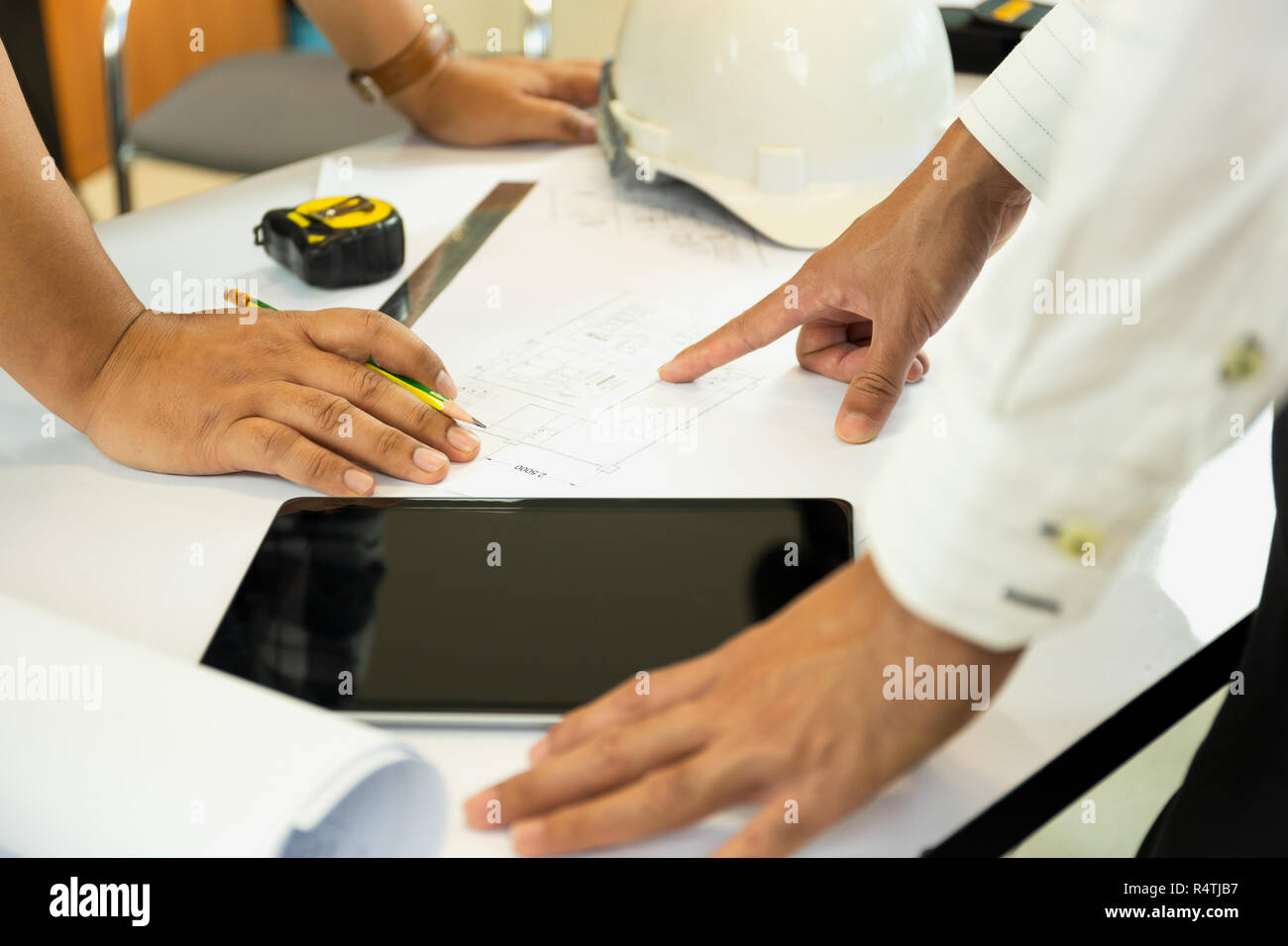 Asian architectuer lavorando sul piano mani puntando al bluepring sketch. Foto Stock