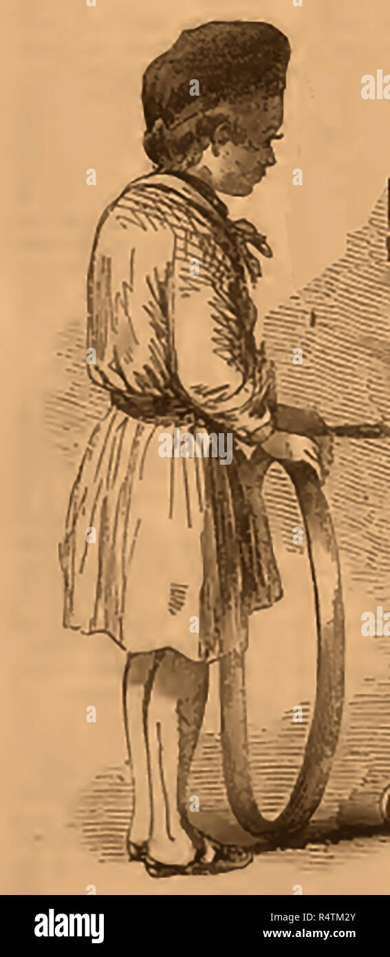 Infanzia vittoriana giochi . Anello di rotolamento o trundling - un ragazzo con canestro e stick Foto Stock