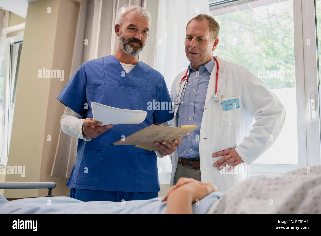 Medici di sesso maschile facendo turni nella stanza di ospedale Foto Stock