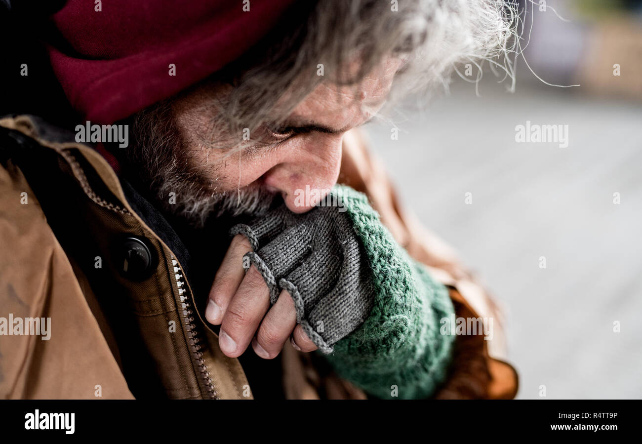 Una vista ravvicinata di senzatetto beggar man standing all aperto in città, strofinando il naso. Foto Stock