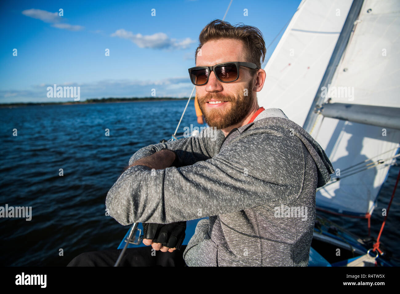 Uomo bello viaggiare in barca. Abbigliamento casual, uomo vestito in felpa  con cappuccio grigia, tempo primaverile, uomo barbuto in occhiali da sole  sulla barca Foto stock - Alamy