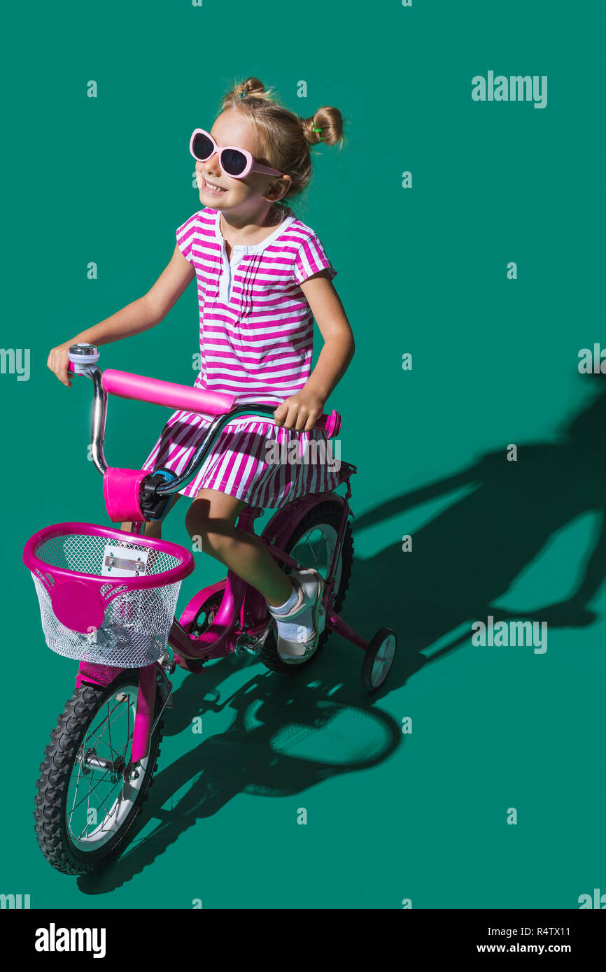 Carefree ragazza Bicicletta Equitazione su sfondo verde Foto Stock
