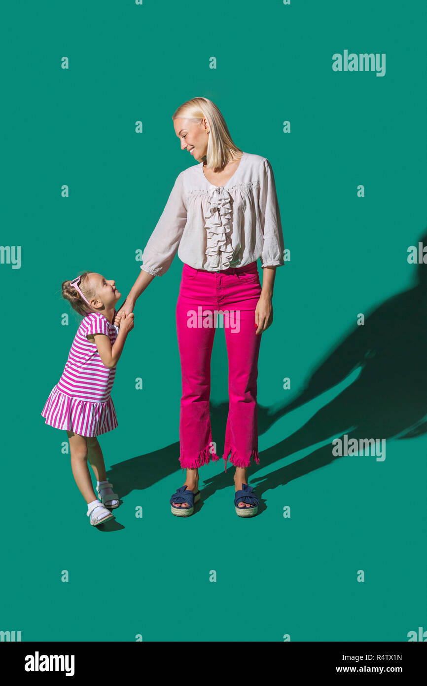 Madre e figlia tenendo le mani su sfondo verde Foto Stock