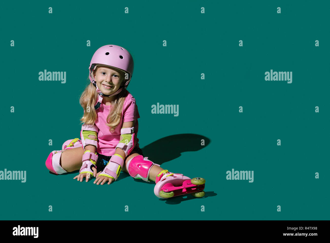 Ritratto sorridente ragazza pattinaggio su sfondo verde Foto Stock