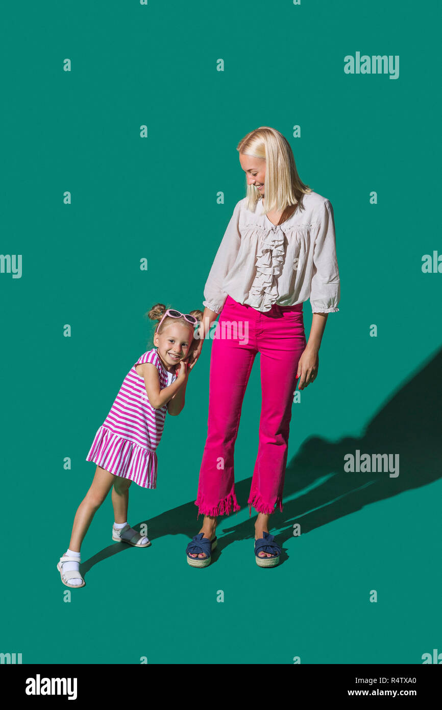 Ritratto di Madre e figlia tenendo le mani contro lo sfondo di colore verde Foto Stock