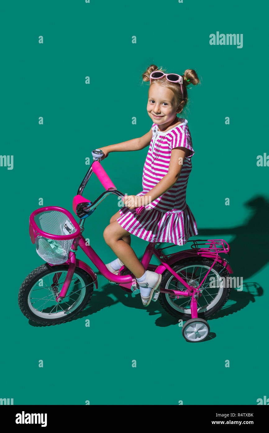 Ritratto sorridente ragazza in bicicletta contro lo sfondo di colore verde Foto Stock