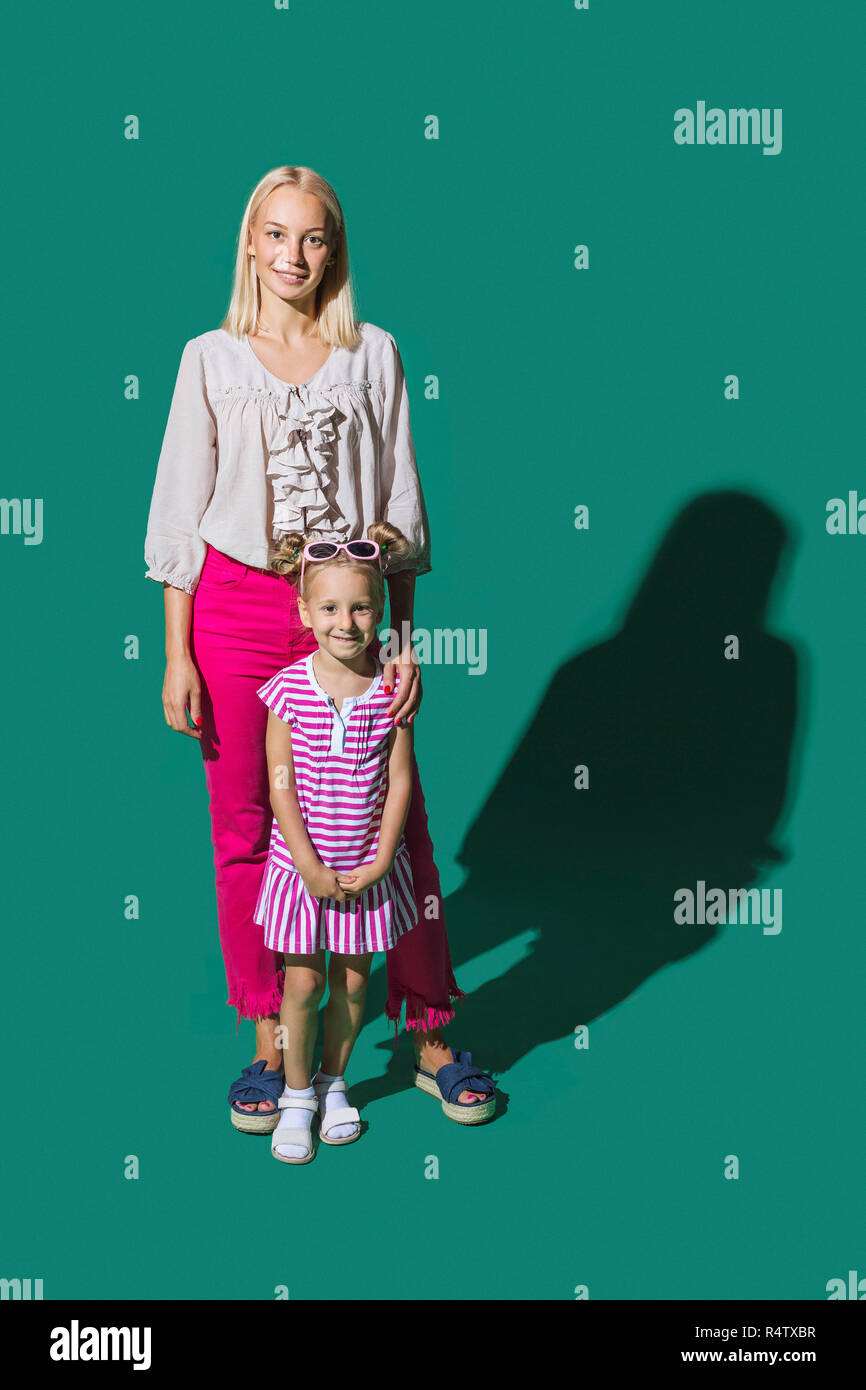 Ritratto sorridente madre e figlia contro lo sfondo di colore verde Foto Stock