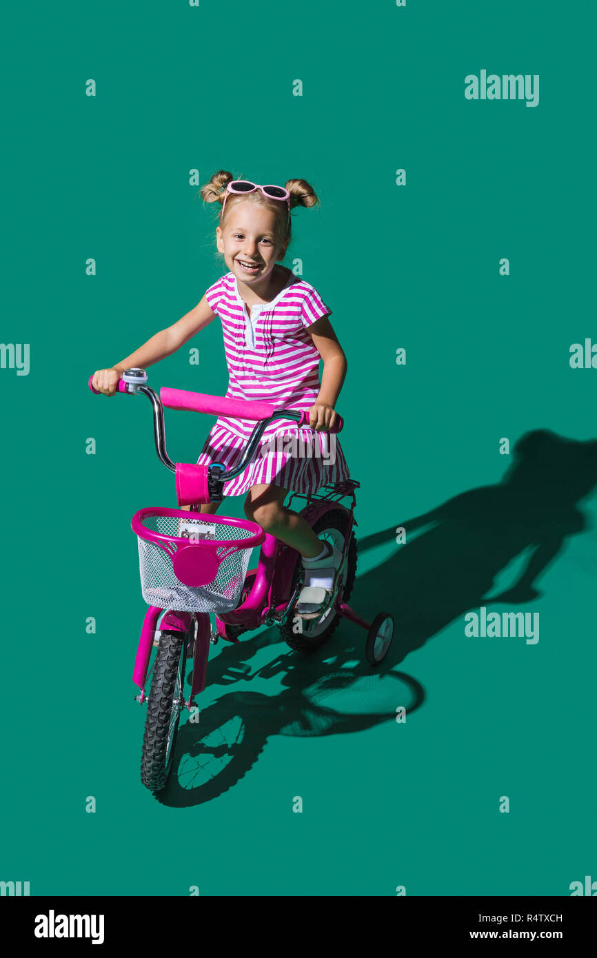 Ritratto sorridente ragazza in bicicletta contro lo sfondo di colore verde Foto Stock