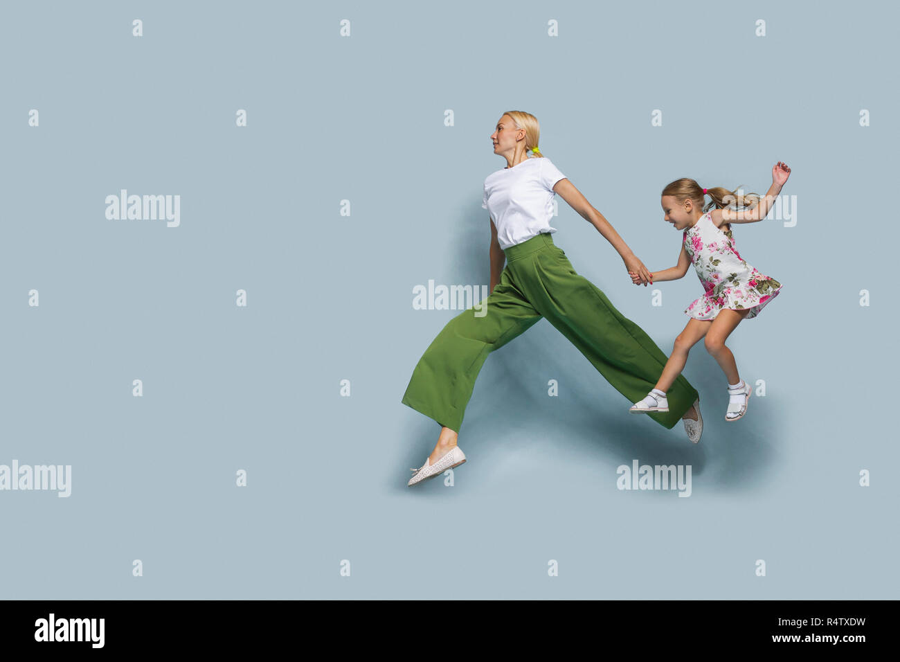 Madre e figlia jumping contro sfondo blu Foto Stock