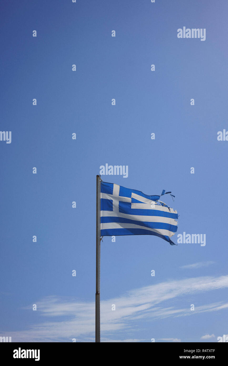 Rip bandiera greca soffiando nel vento contro sunny blue sky Foto Stock