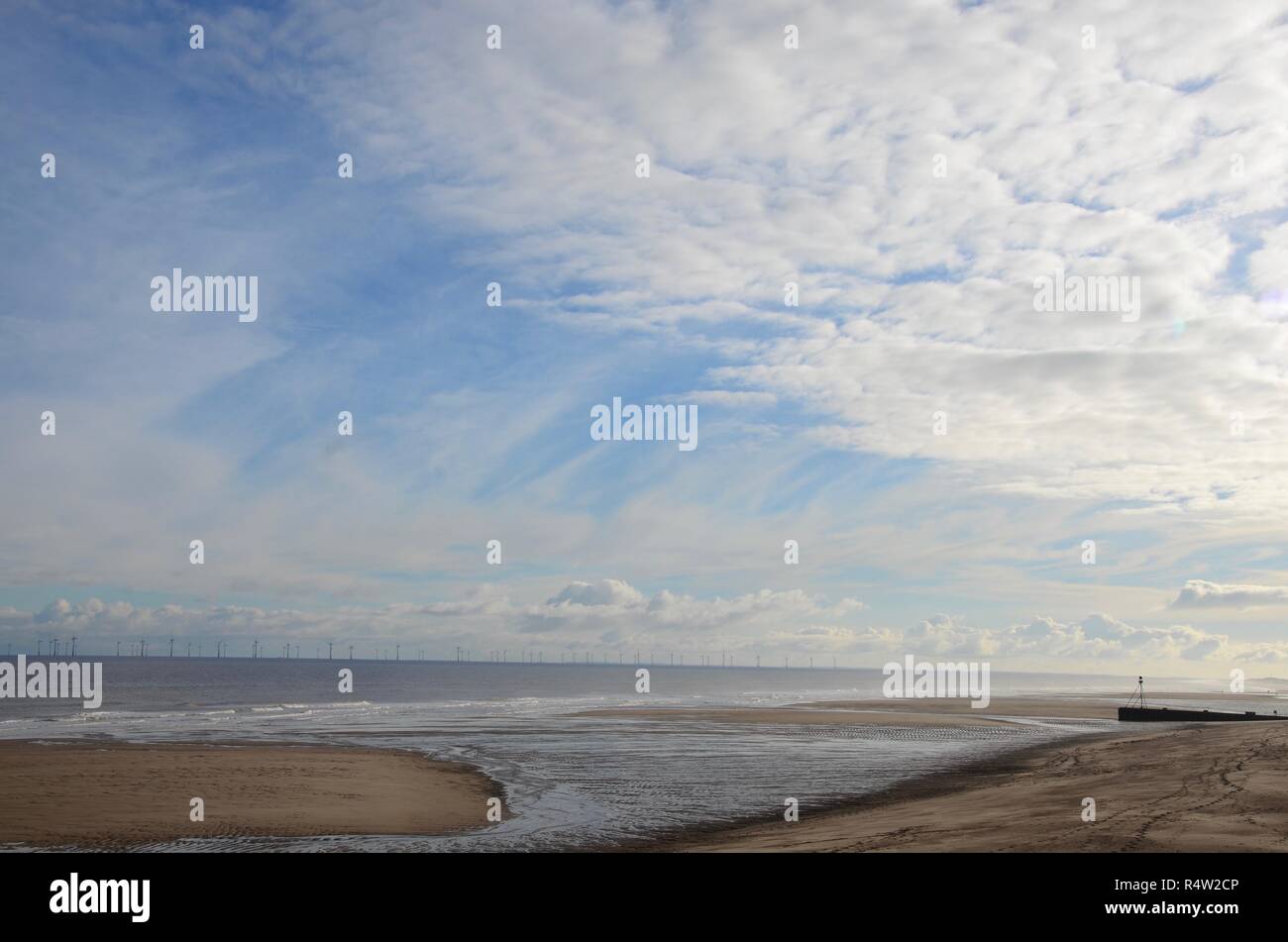 Svuotare seascape con grande open sky, nuvole e delle turbine a vento all'orizzonte, Lincolnshire, Inghilterra. Foto Stock