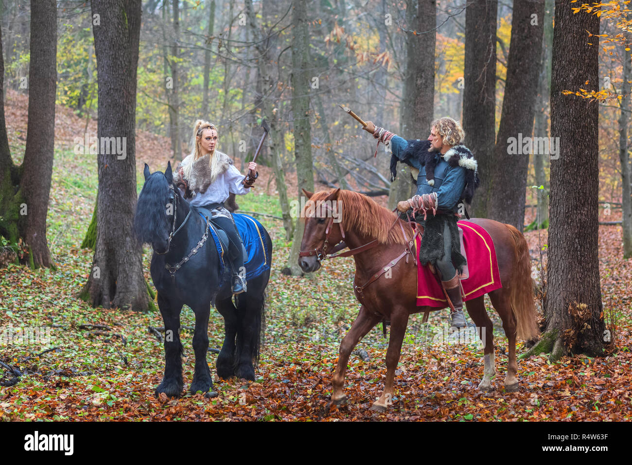 2 (due) pericolosi scandinavian viking guerrieri a cavallo e assi di sollevamento sopra la testa nella foresta. Northern guerrieri vichinghi pronti a raid Foto Stock