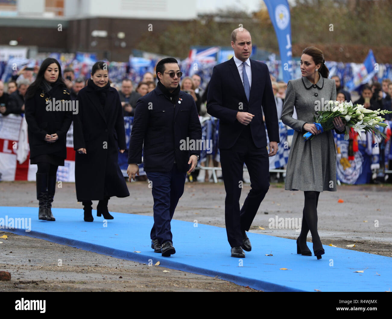 Il Duca e la Duchessa di Cambridge, accompagnati dalla famiglia del proprietario di Leicester City Vichai Srivaddhanaprabha, posano fiori nel sito tributo vicino al King Power Stadium del Leicester City Football Club, durante una visita a Leicester per rendere omaggio a coloro che sono stati uccisi durante il crollo dell'elicottero il mese scorso. Foto Stock