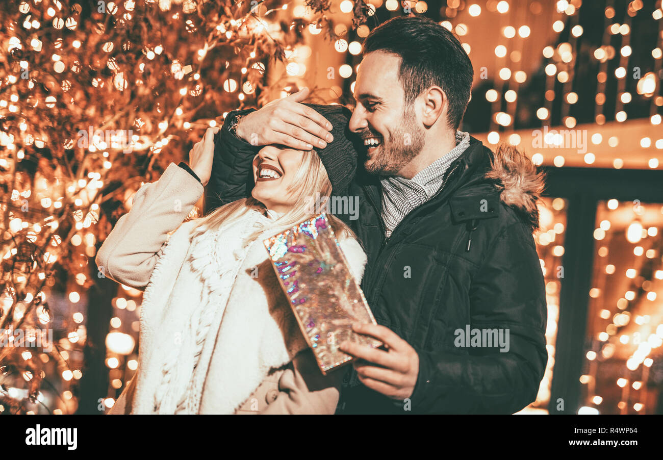 L'uomo mantiene la sua ragazza gli occhi coperti mentre ella dando un regalo per la festa di Natale. Foto Stock