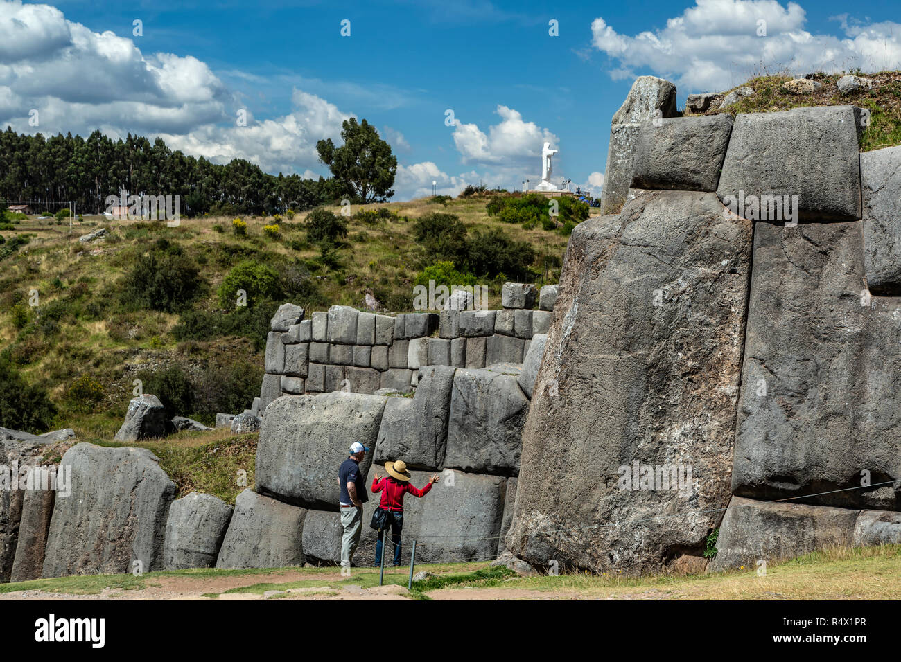 Matura in piedi di fronte a grandi mura difensive e Cristo Blanco (bianco Cristo) in background, fortezza Inca di Sacsaywaman, Cusco, Perù Foto Stock