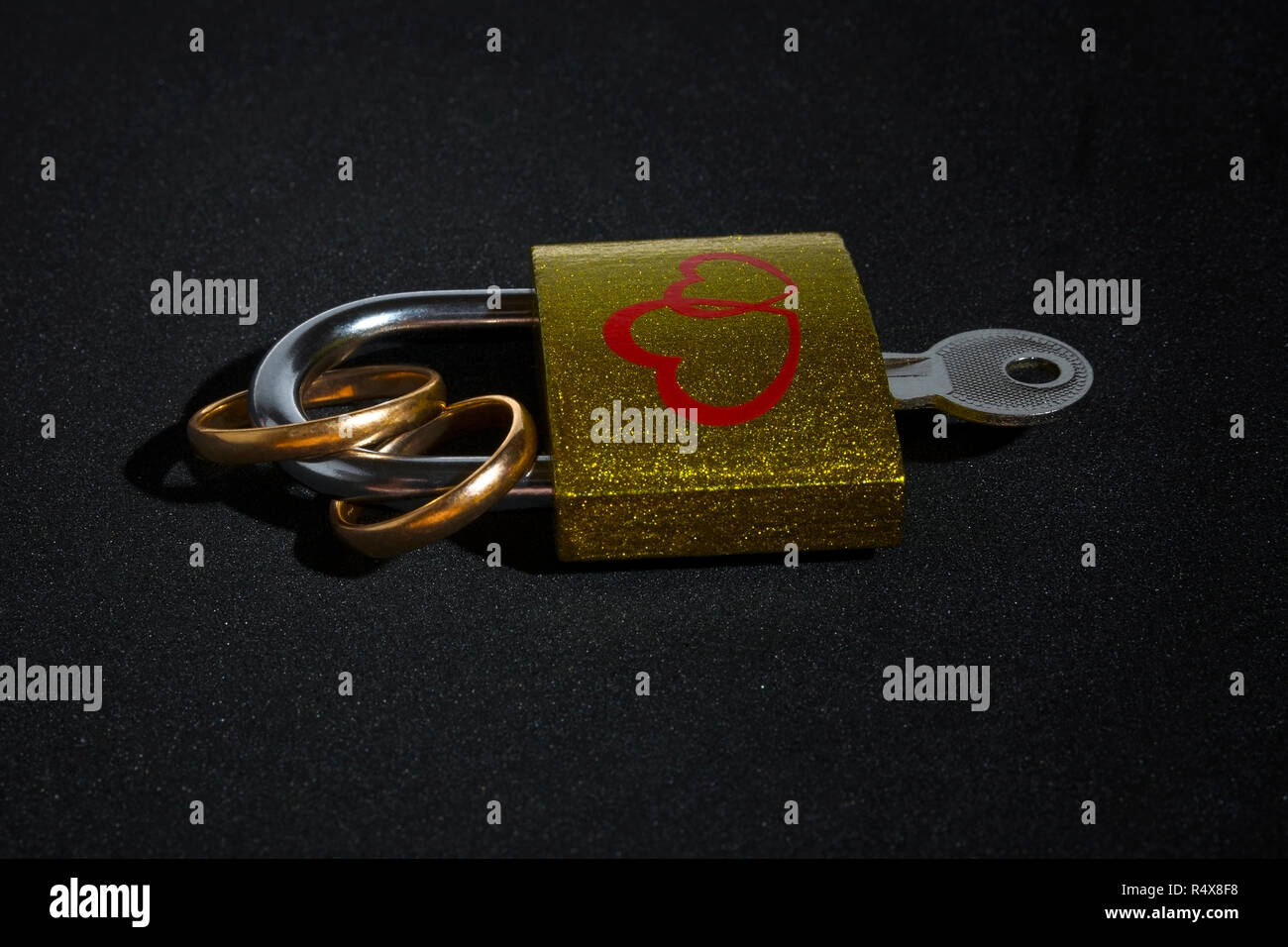 Gli anelli di nozze e lucchetto isolata su uno sfondo nero. Il concetto di matrimonio o di matrimonio. Il giorno di San Valentino. Foto Stock