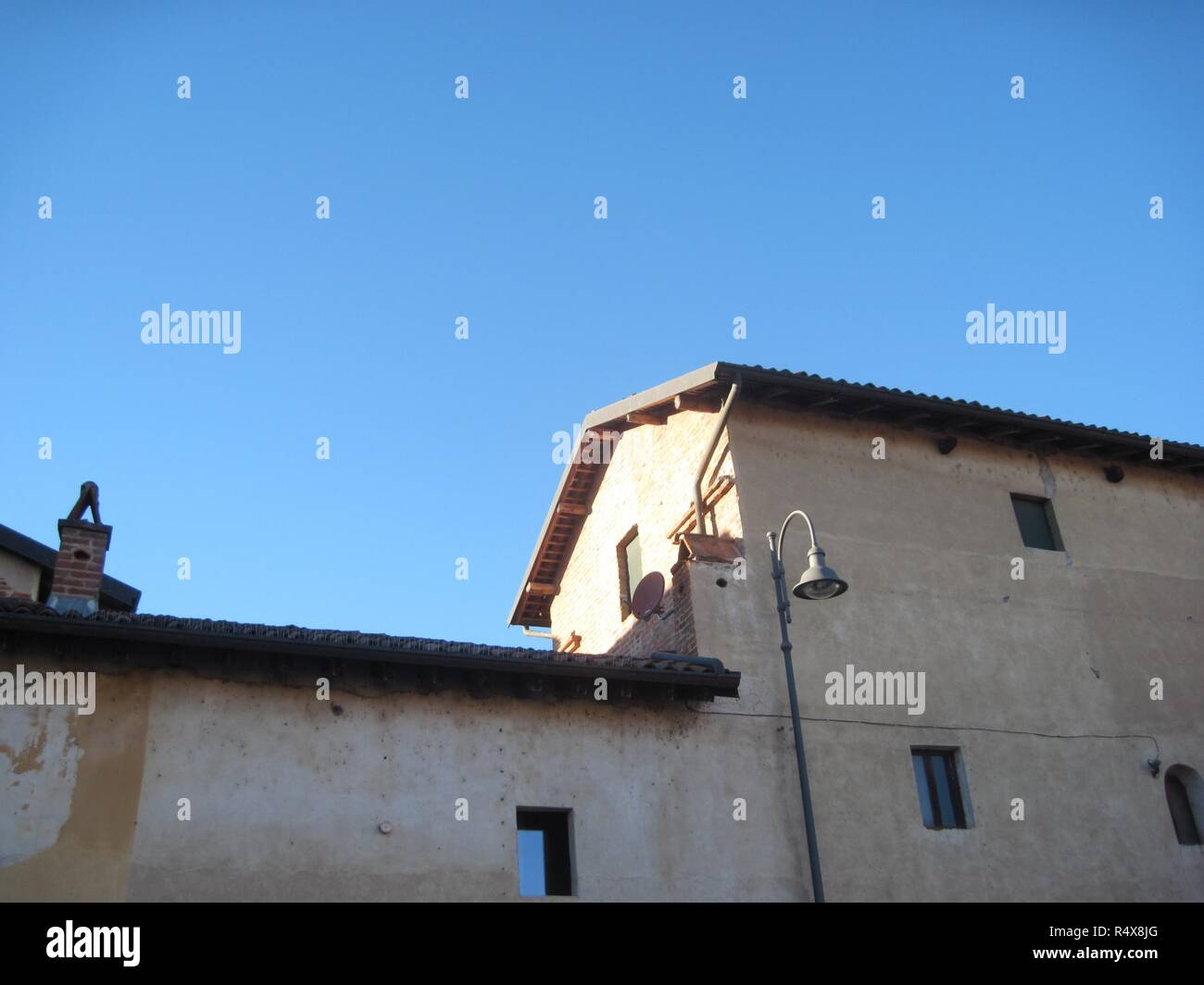 Una tradizionale cascina piemontese (cascina) durante una chiara soleggiata giornata invernale con alcune vecchie mura e un lampione, in Cavagliano, Bellinzago, Italia Foto Stock