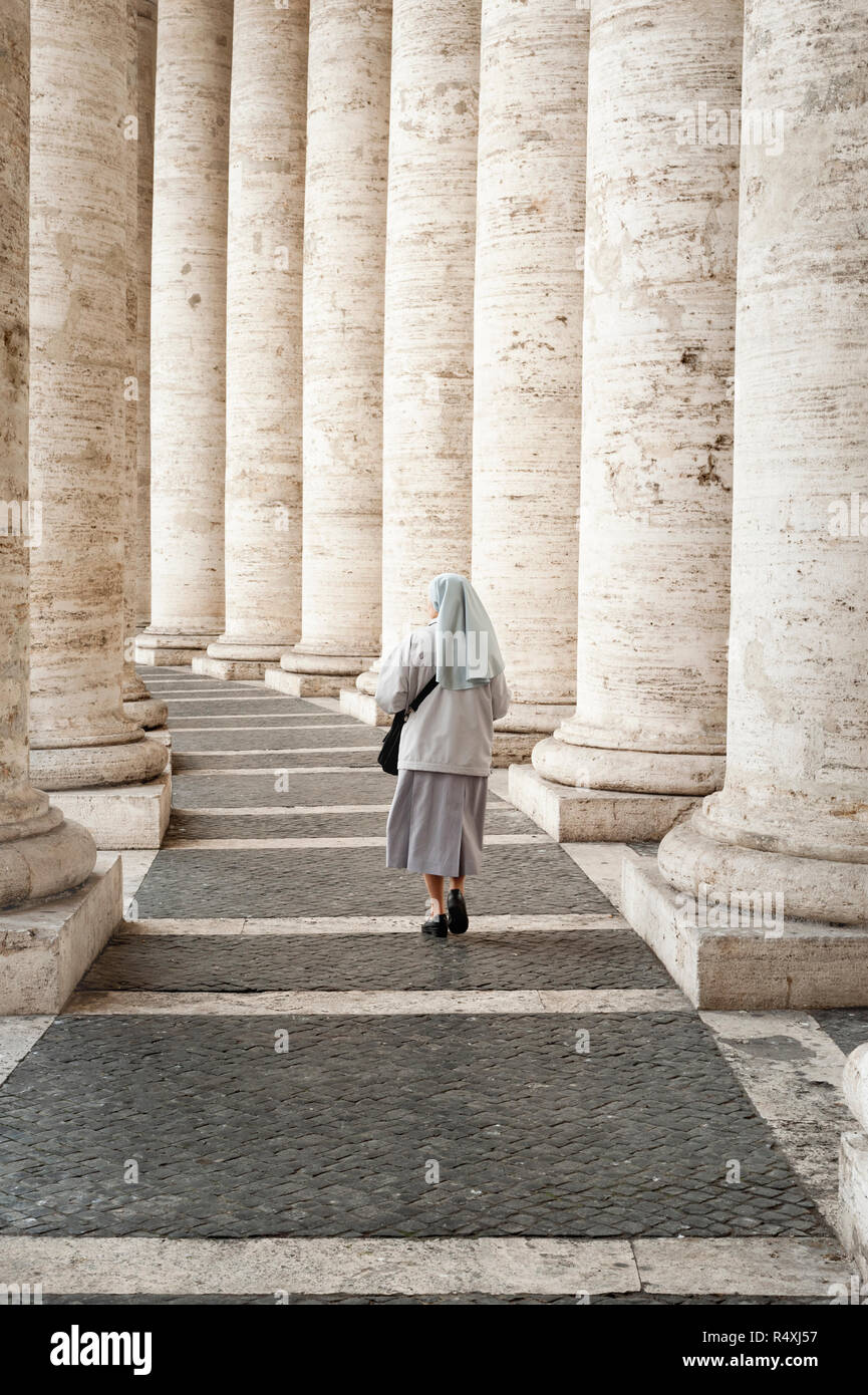 Nun a piedi attraverso del Bernini colonnato dorico a San Pietro in Vaticano Roma Foto Stock