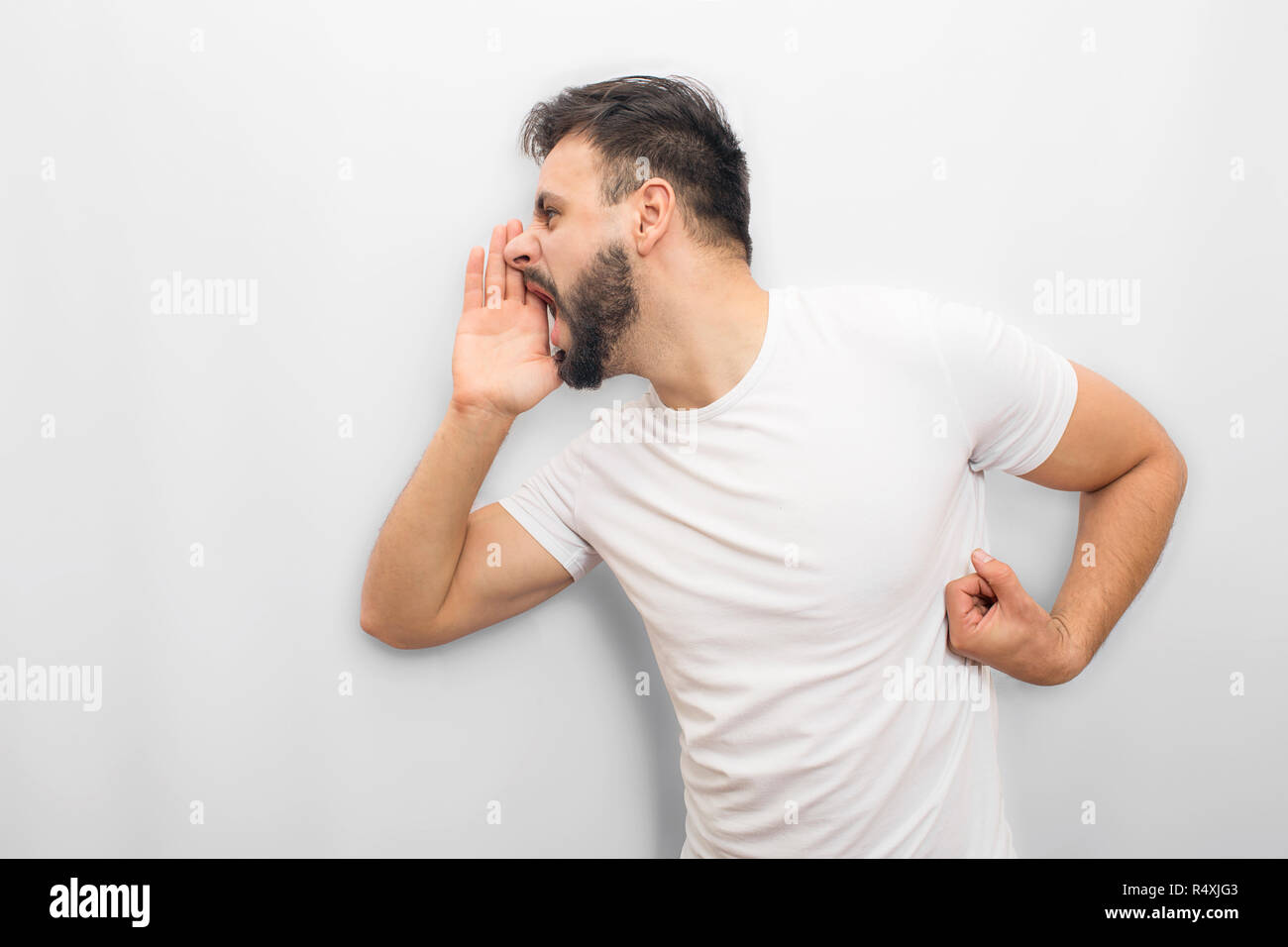 Emotional Man che esprime i suoi sentimenti. Egli grida e urla. Guy coveres la bocca con la mano da un lato. Isolato su sfondo bianco. Foto Stock