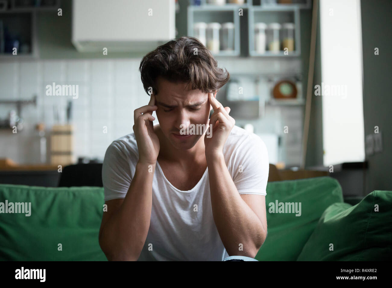 Giovane uomo seduto sul divano di casa hanno un mal di testa Foto Stock