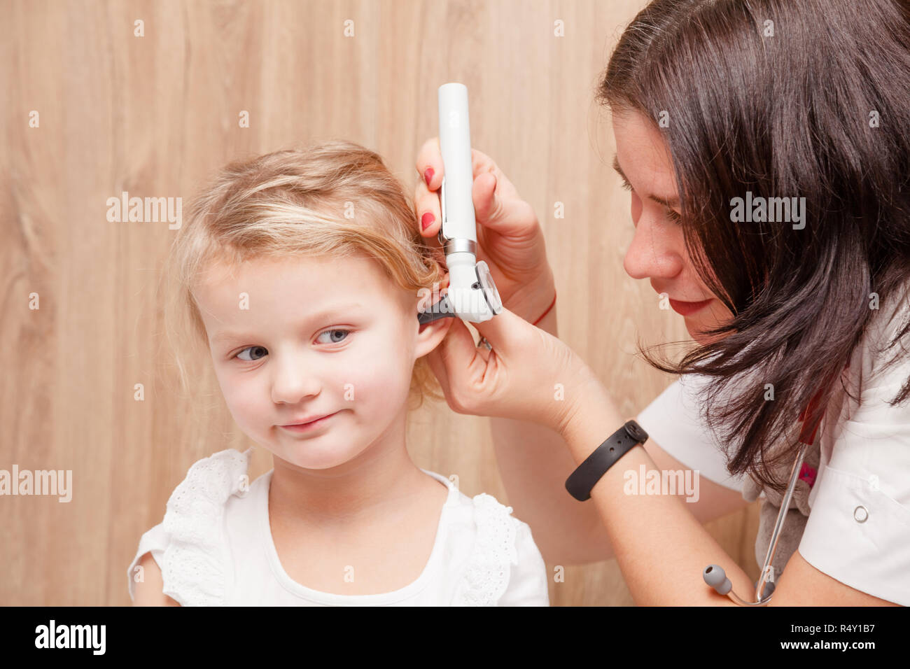 Femmina esamina pediatra bambina l orecchio. Medico utilizzando un otoscopio o auriscope per controllare il canale uditivo e la membrana del timpano. Bambino ENT concetto di controllo Foto Stock