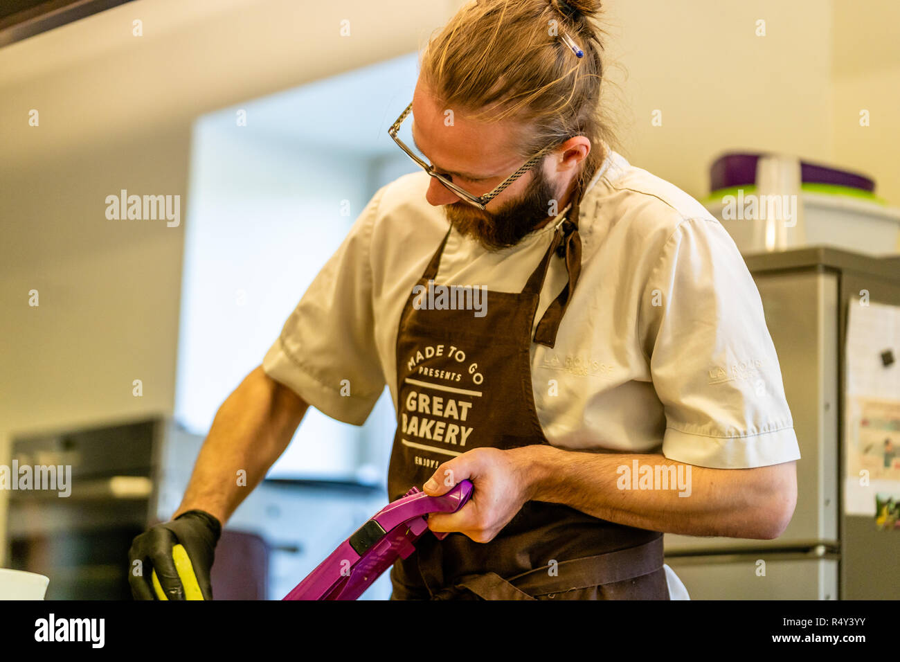 Lo Chef maschio Tagliare le melanzane in cucina - con guanto sulla mano Foto Stock