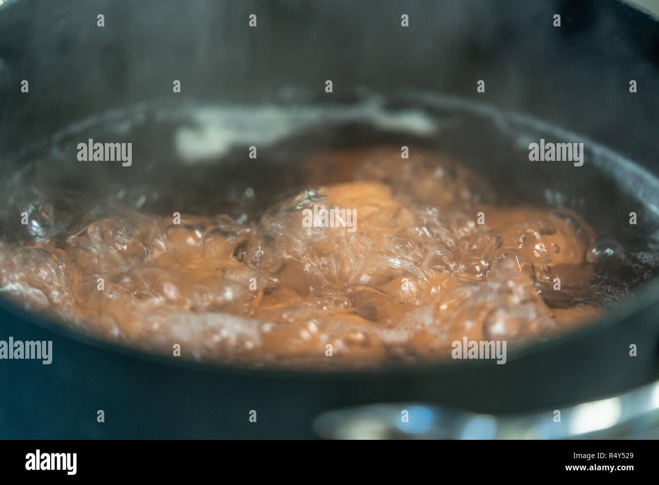 Bollire le uova in acqua - Primo piano con il fumo che copre parzialmente il telaio Foto Stock