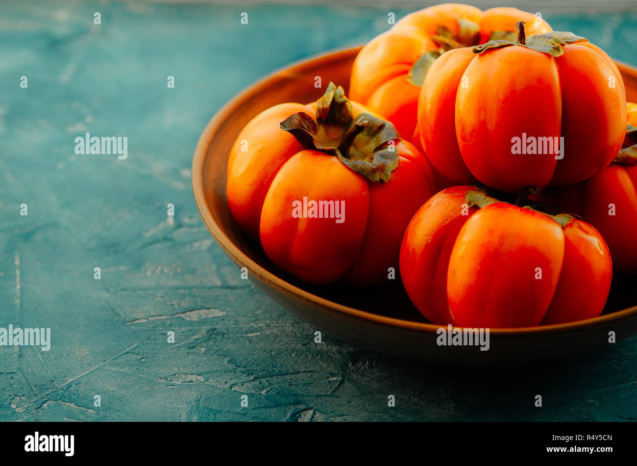 Persimmon è una fonte di calcio, una fonte di potassio, carboidrati. Arance mature persimmon frutto in una piastra di ceramica. Foto Stock