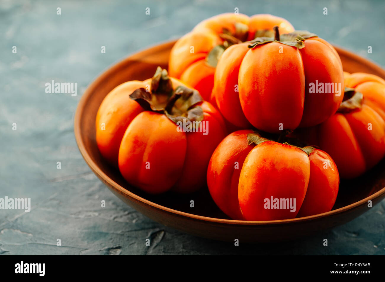 Persimmon è una fonte di calcio, una fonte di potassio, carboidrati. Arance mature persimmon frutto in una piastra di ceramica. Foto Stock
