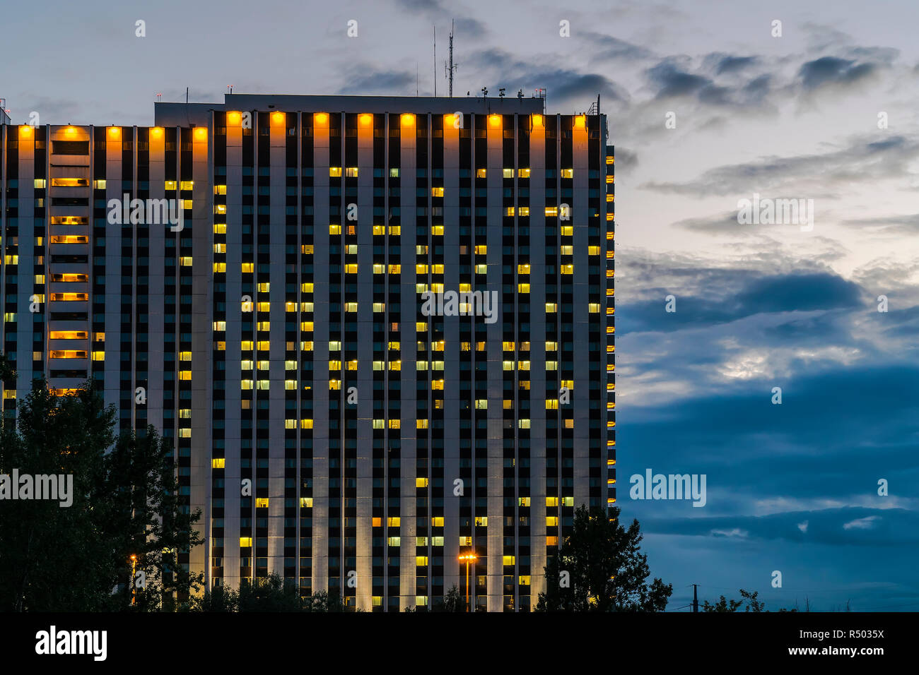 Le finestre del grande hotel sono calorosamente splendente contro lo sfondo del cielo in tempesta Foto Stock