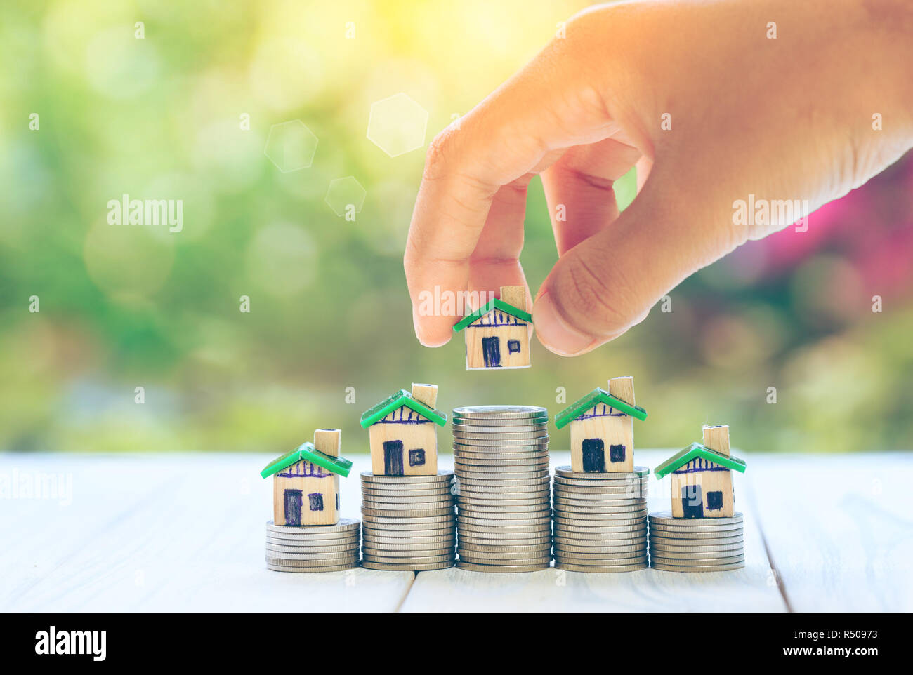 Casa inserito sulle monete di uomini la mano della pianificazione è il risparmio di denaro monete per comprare una casa concetto concetto per la proprietà Scala, ipotecari e immobiliari investire Foto Stock