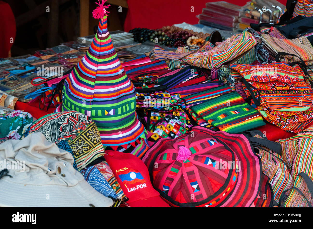 Una selezione di locali colorati merchandise, cappelli, sciarpe,borse e negozio di souvenir per la vendita sul mercato - stallo Luang Prabang, Laos, Lao Foto Stock