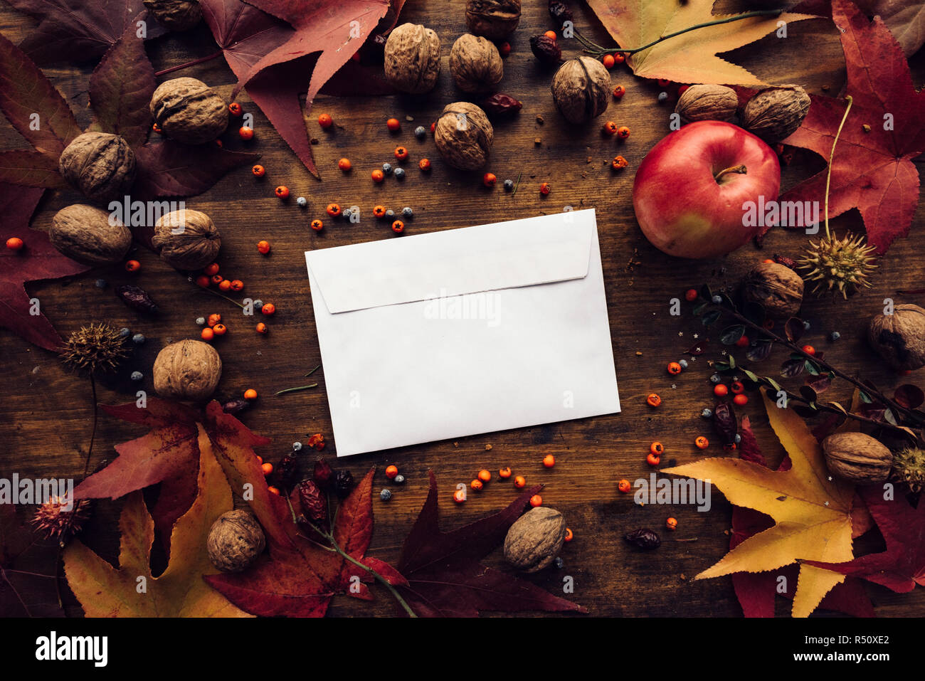 Autunno busta posta flat lay mock up sul tavolo in legno decorato a secco con foglie di acero e frutta di stagione Foto Stock
