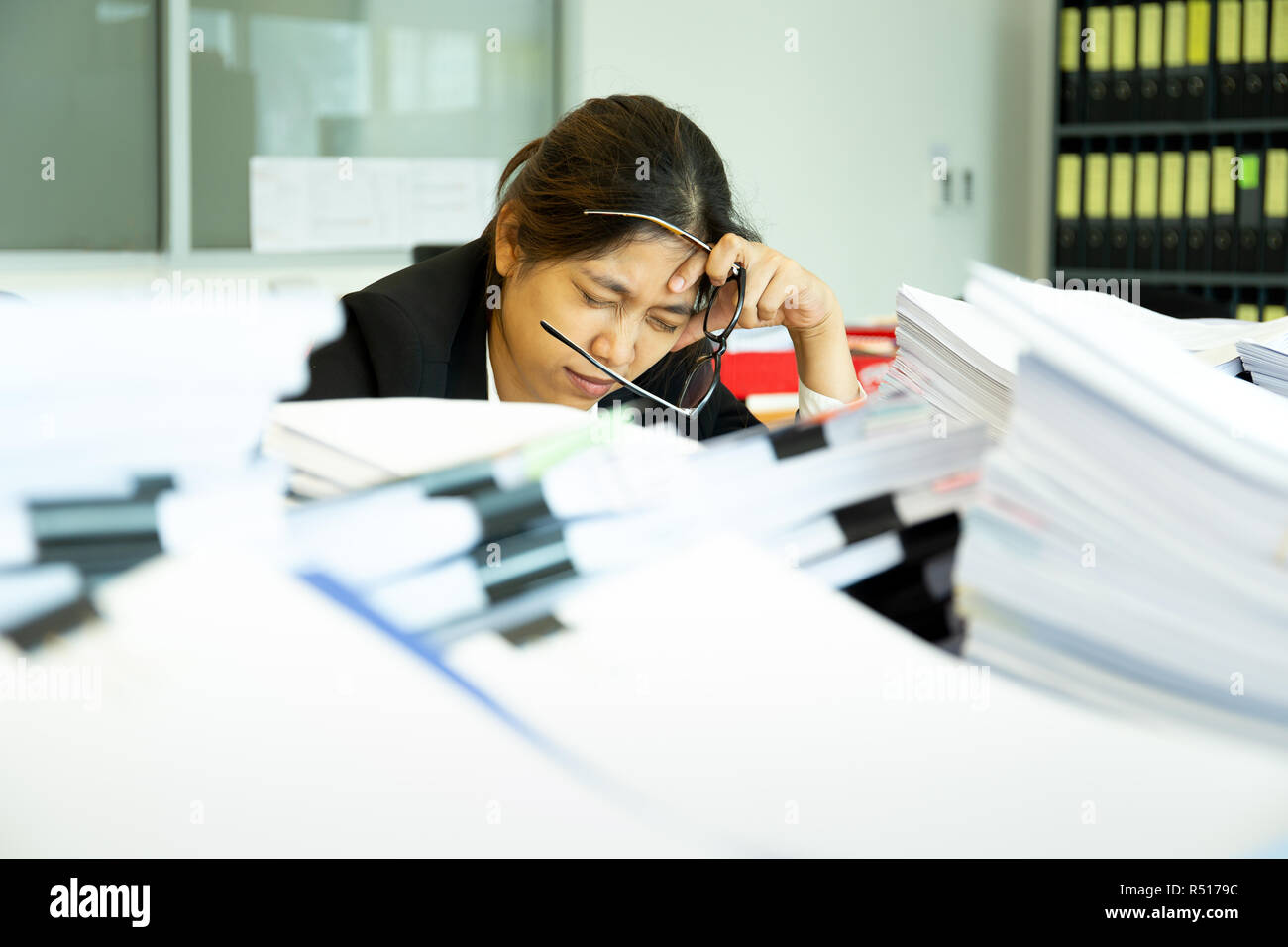 Imprenditrice in appoggio le mani sulla testa con gli occhi vicino alla scrivania in ufficio. Foto Stock