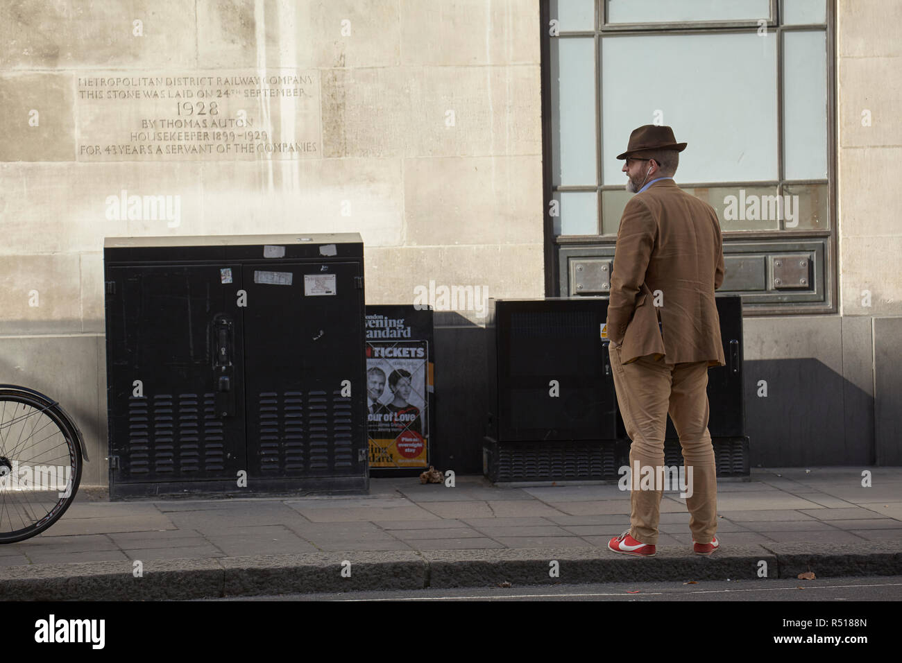 Uomo in attesa a St. James Park Station con una placca del Metropolita azienda ferroviaria sulla parete. Foto Stock