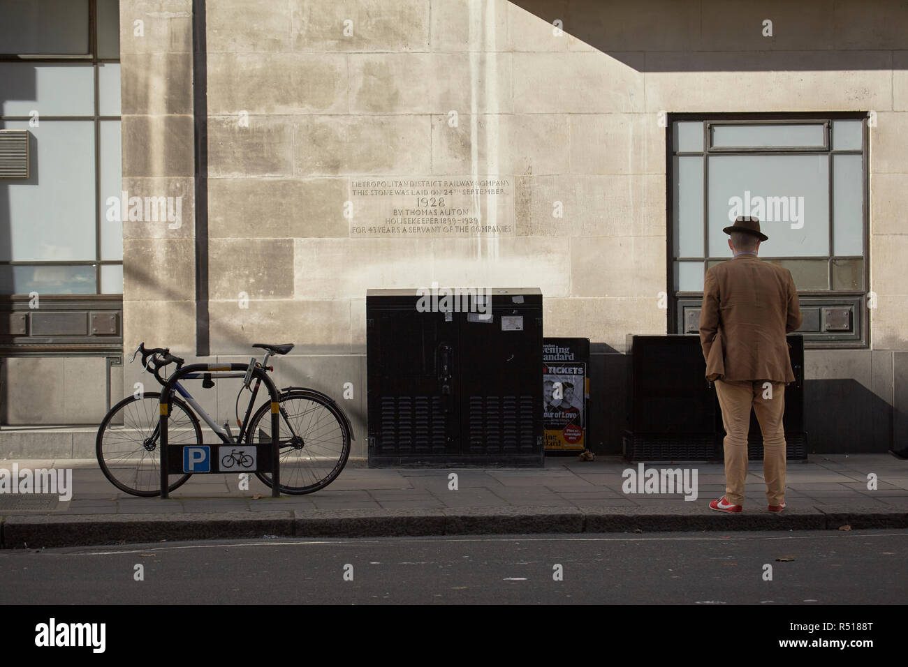 Uomo in attesa a St. James Park Station con una placca del Metropolita azienda ferroviaria sulla parete. Foto Stock