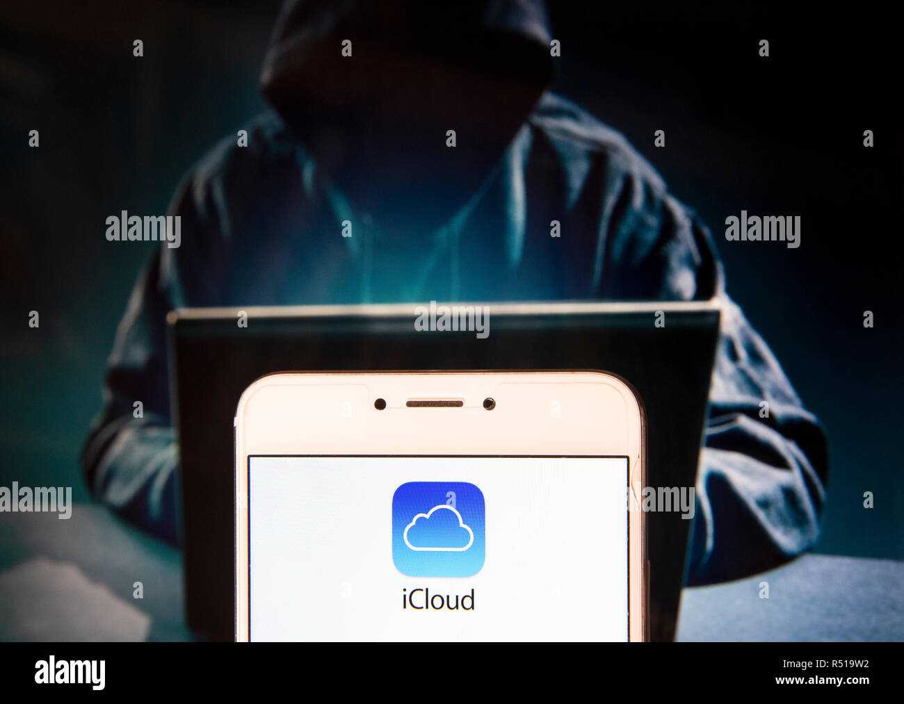 American file hosting società di servizio di proprietà di Apple e icloud, il logo è visibile su un androide dispositivo mobile con una figura di hacker in background. Foto Stock