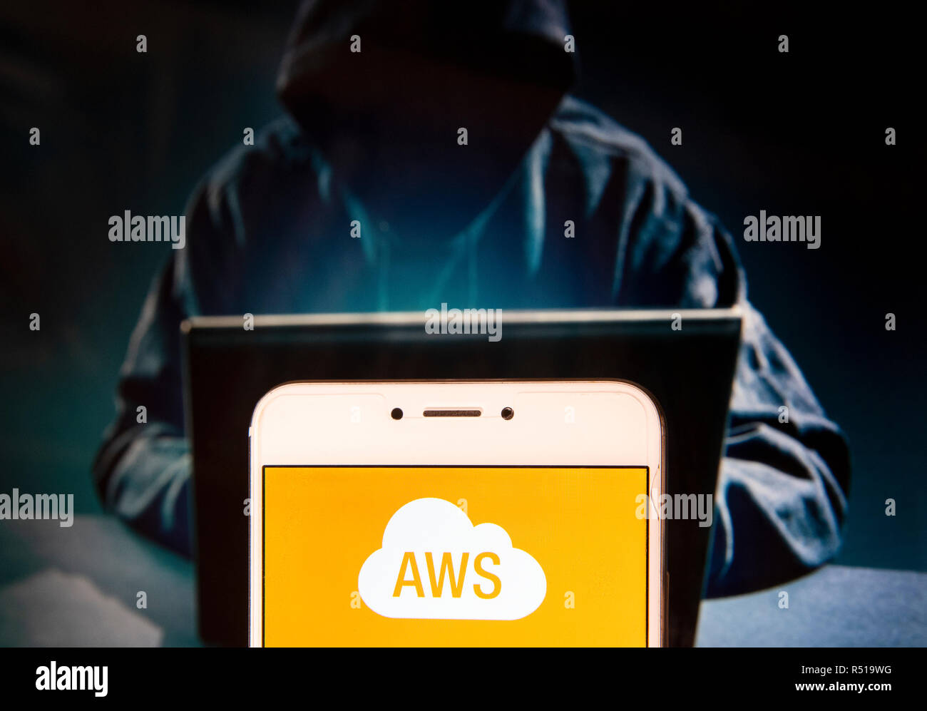 American on-demand piattaforma di cloud computing di proprietà di Amazon,Amazon Web Services (AWS), il logo è visibile su un androide dispositivo mobile con una figura di hacker in background. Foto Stock