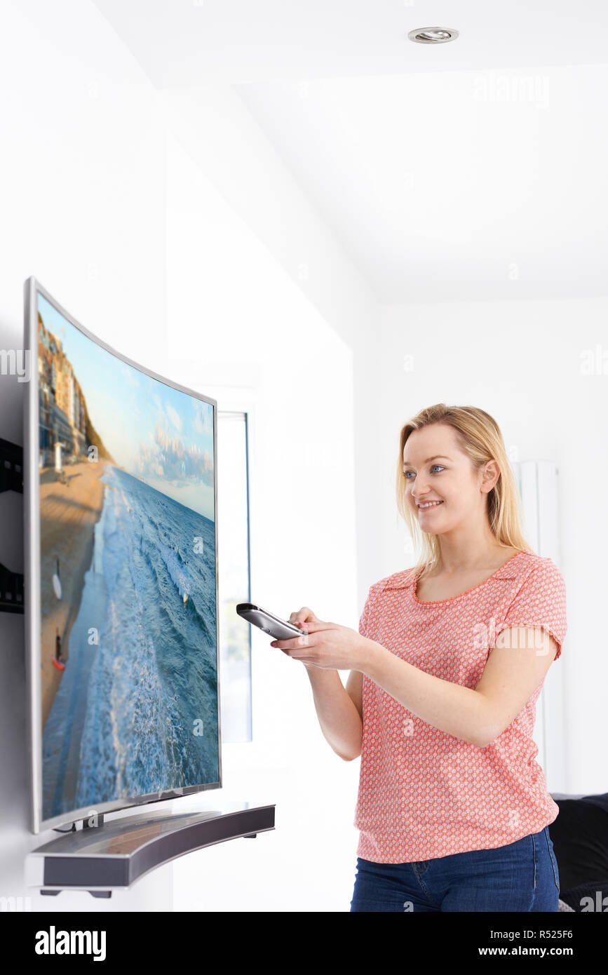 Giovane donna con il nuovo schermo curvo la televisione a casa Foto Stock