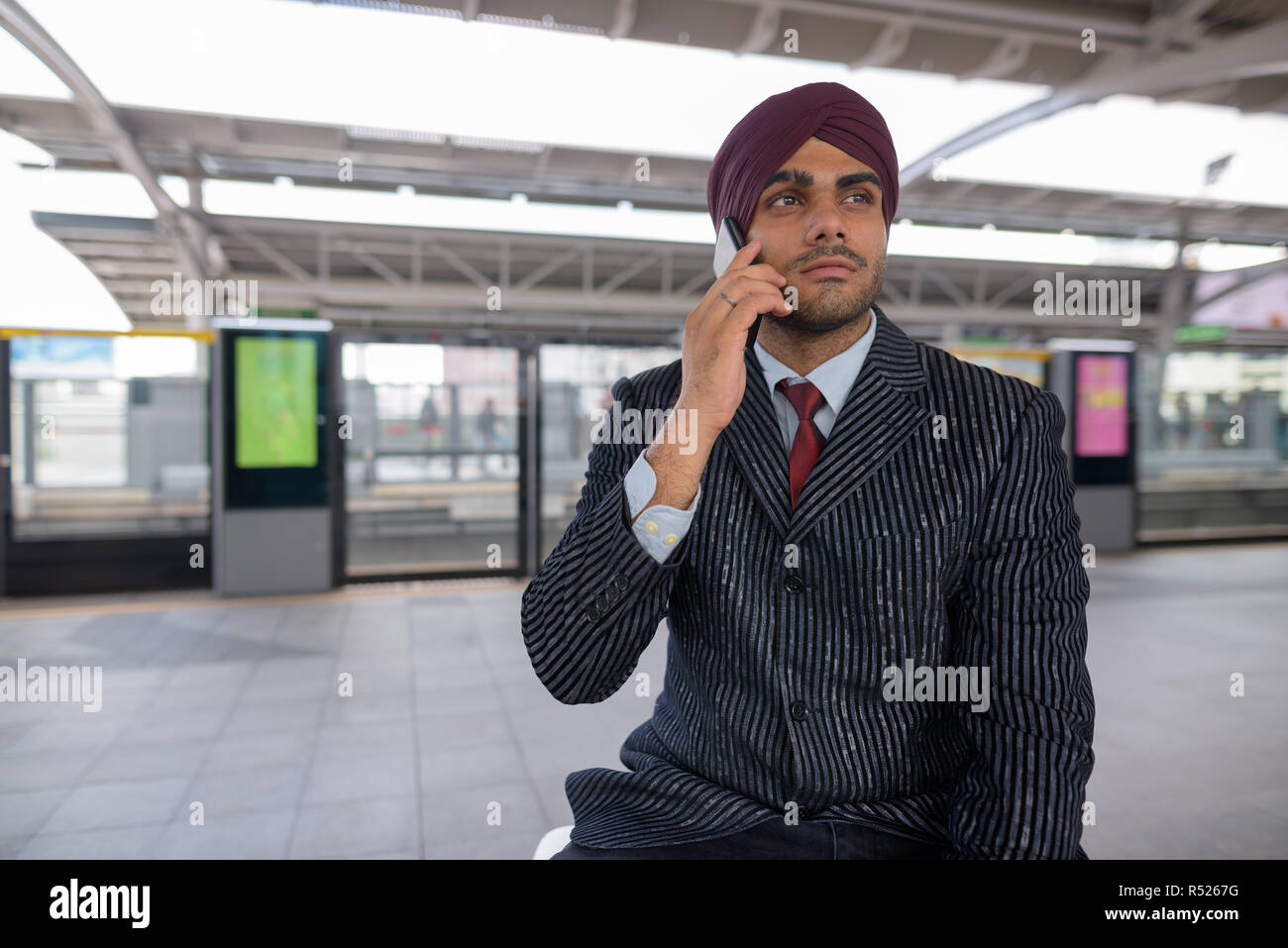 Commerciante indiano parlando al telefono alla stazione ferroviaria Foto Stock