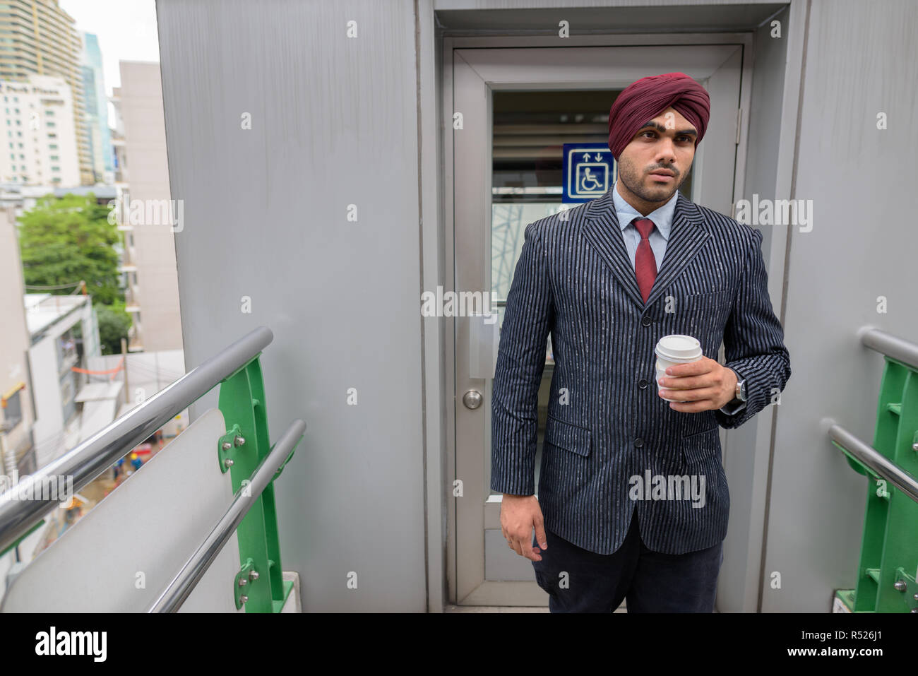 Ritratto di commerciante indiano con turbante all aperto in città azienda tazza da caffè Foto Stock