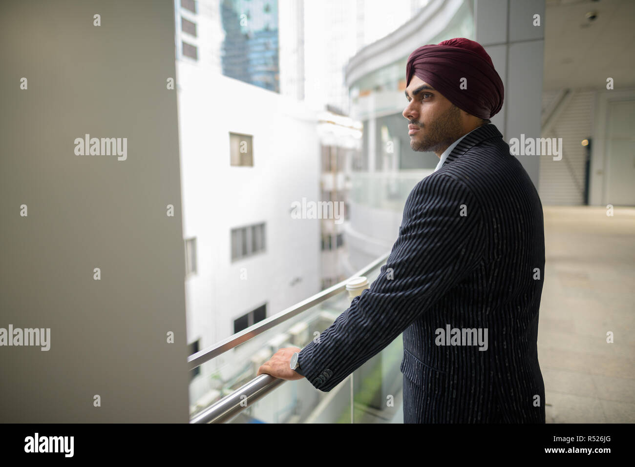 Ritratto di commerciante indiano con turbante pensando all'aperto in città Foto Stock