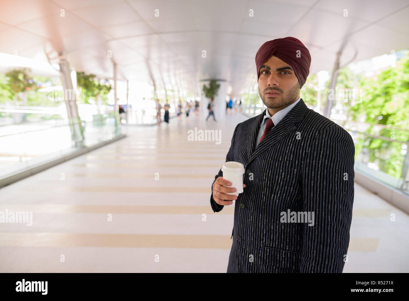 Commerciante indiano con turbante all aperto in città azienda tazza da caffè Foto Stock