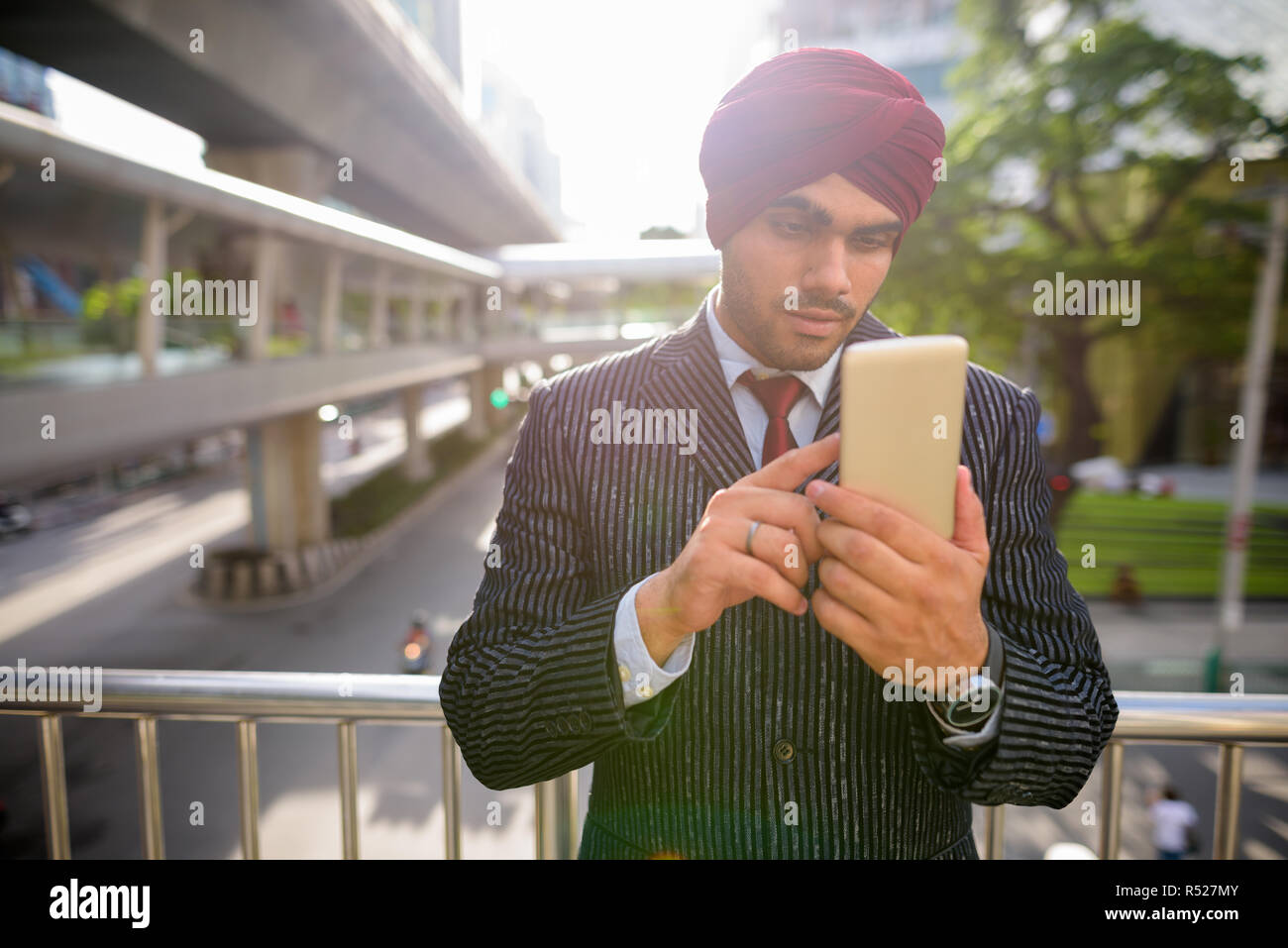Commerciante indiano all'aperto in città utilizzando il telefono con lens flare Foto Stock