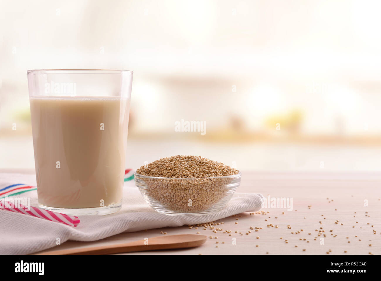 La quinoa drink e grani di cereale nella ciotola su una tavola di legno in cucina. Composizione orizzontale. Vista frontale Foto Stock