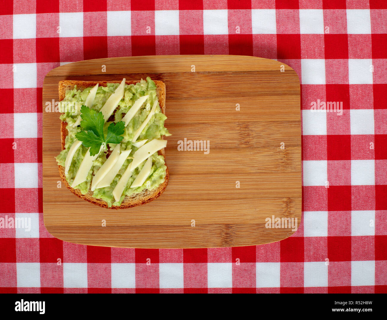 Sana colazione panino sulle fette di pane tostato con avocado e formaggio su sfondo di legno. Lay piatto vista dall'alto. Foto Stock