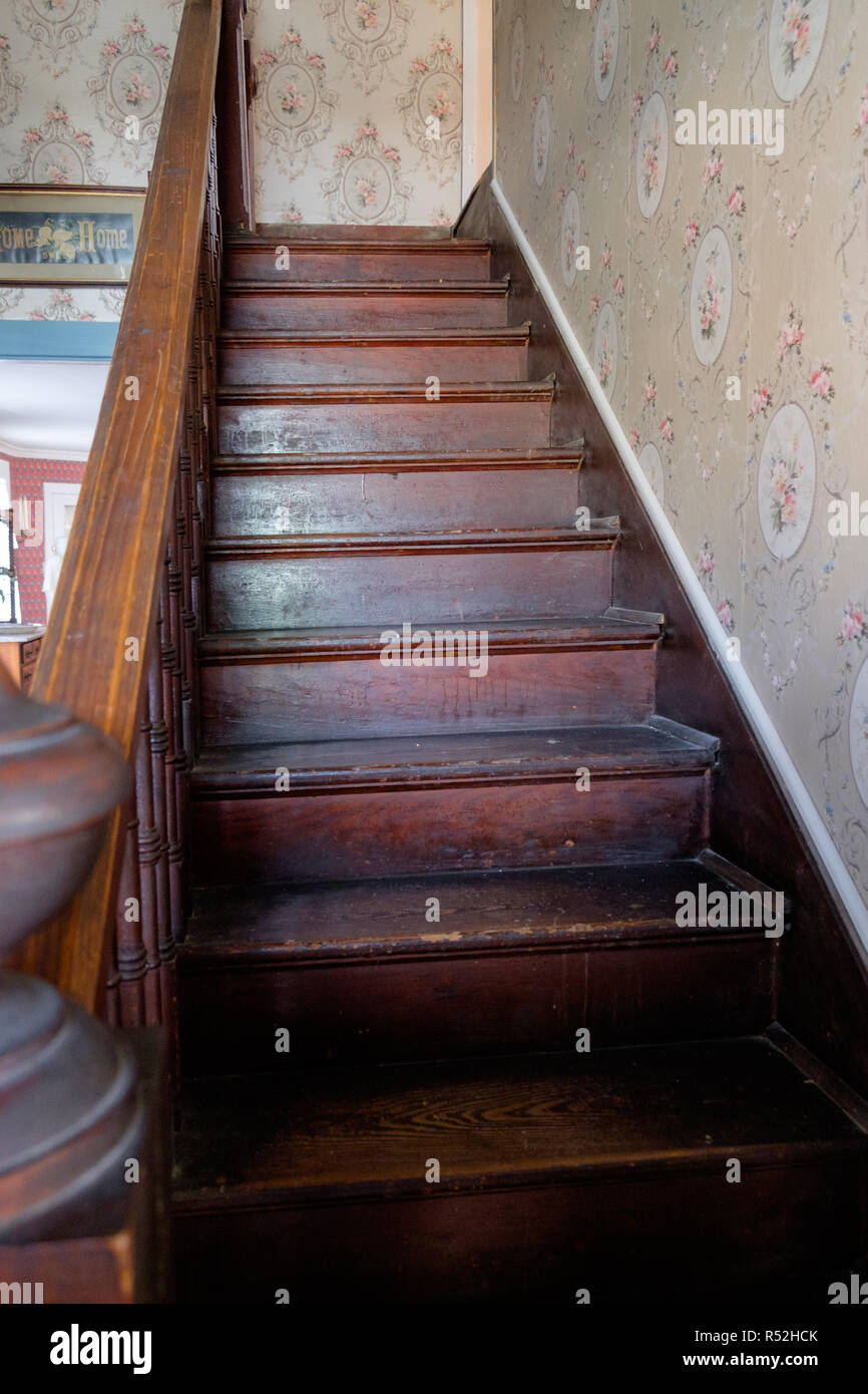 Vecchia scala di legno e corrimano vintage con carta da parati a fiori. Home interno, Piazza di castagno villaggio storico, McKinney,Texas. Foto Stock