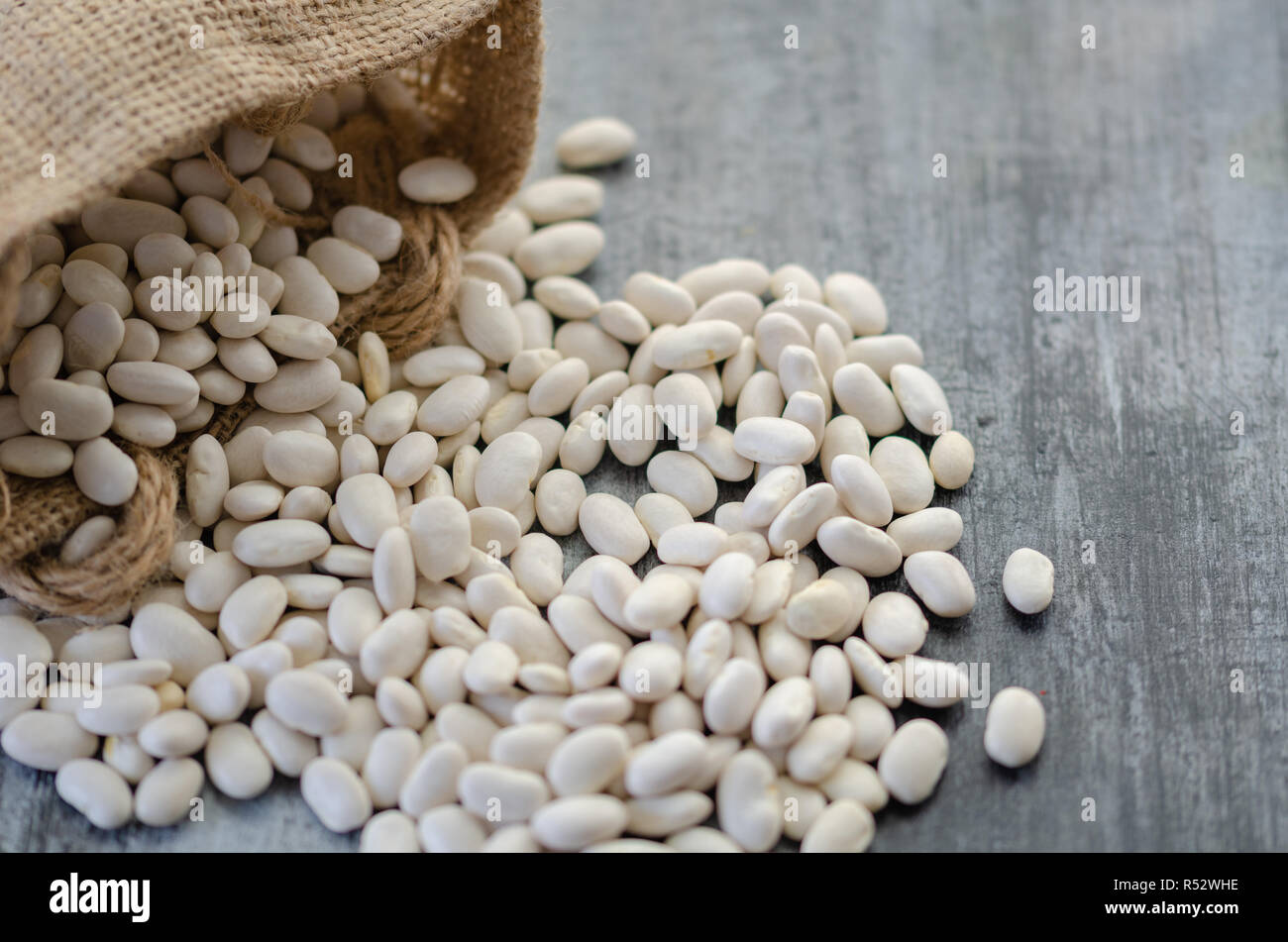 Fagioli nel sacco di tela su sfondo di legno Foto Stock