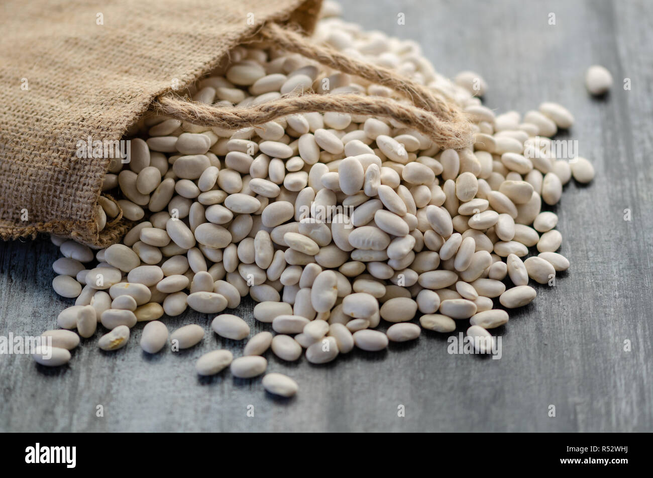 Fagioli nel sacco di tela su sfondo di legno Foto Stock